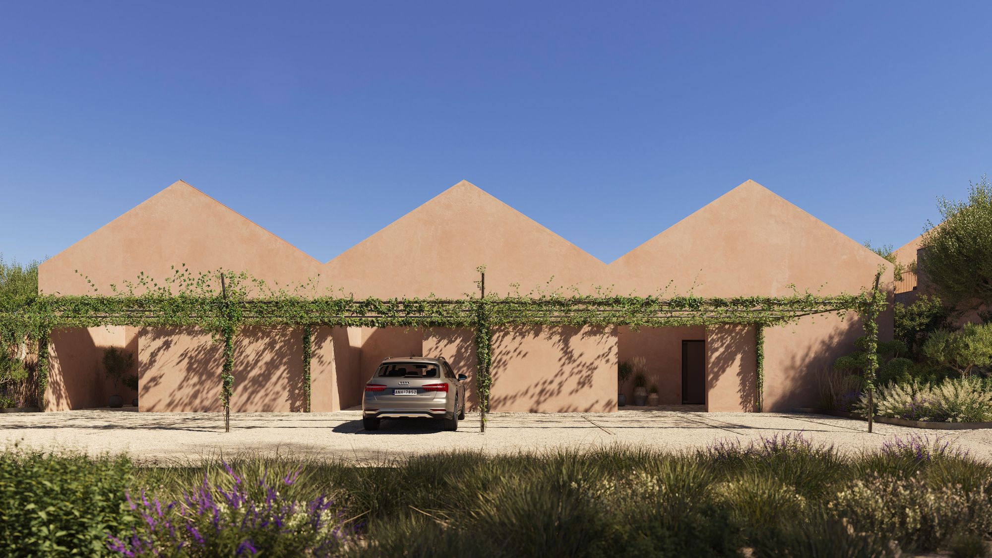 Casa Horizonte from the lane: a row of three terracotta-plastered gables above a vine-covered pergola and gravel parking