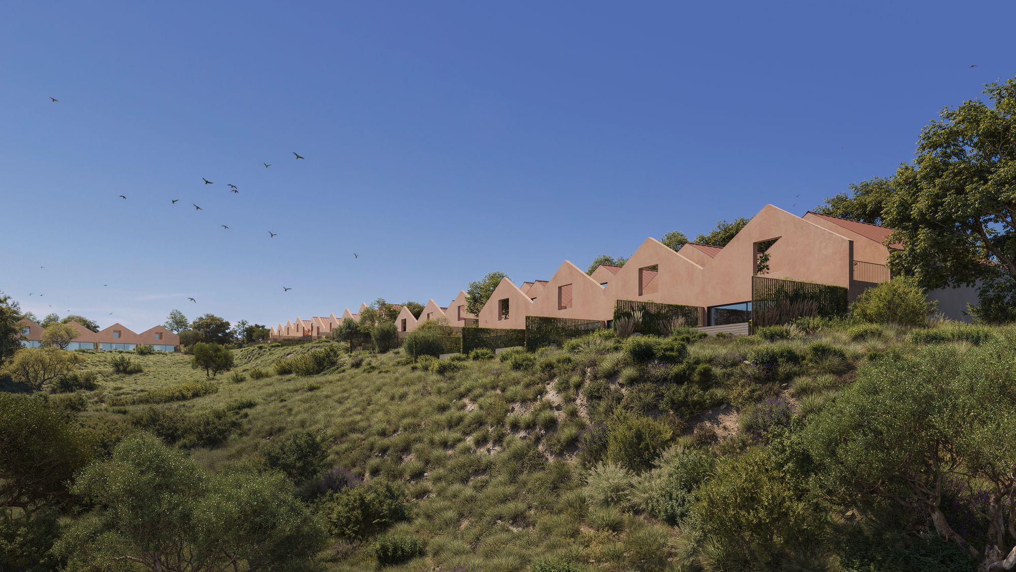 The village of Villa Alba: a row of townhouses in warm terracotta plaster with pitched roofs along a green hillside under a blue sky