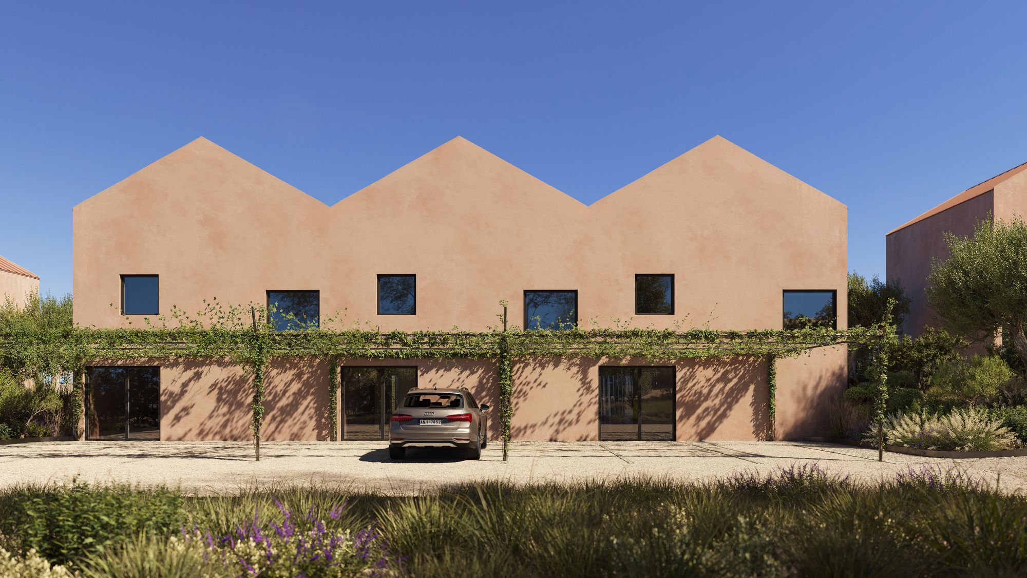 Casa Miradouro from the lane: three tall terracotta-plastered gables with square windows above a vine-covered pergola and gravel parking
